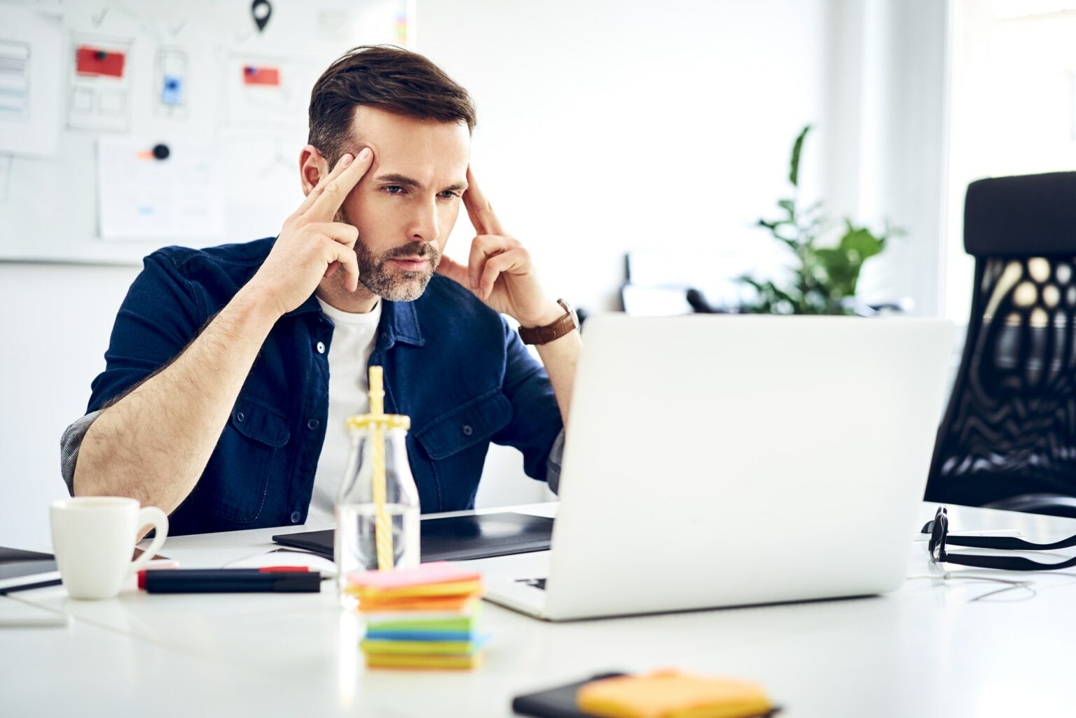 Focused businessman working on laptop at desk in office